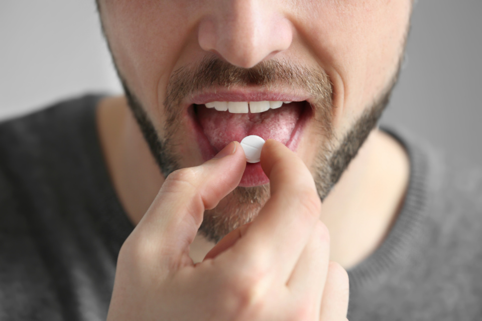 Man putting a pill on his tongue